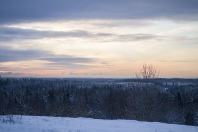 Snow covered landscape against sky during sunset