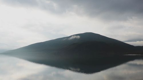 Scenic view of lake by mountains against sky