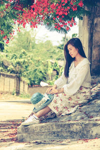 Full length of woman sitting by tree