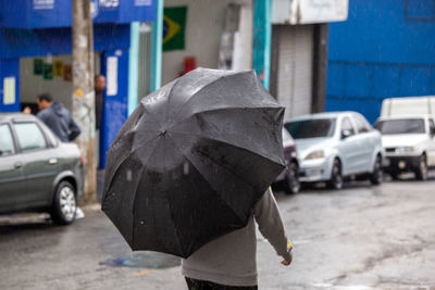 Rear view of woman with umbrella walking on street