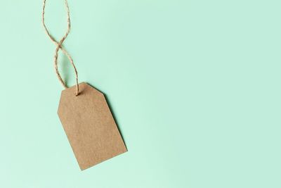 Close-up of paper hanging on rope against blue background