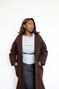 Portrait of young woman standing against white background