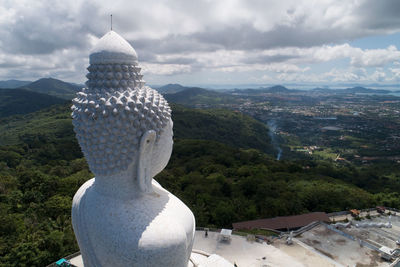 Statue of buddha and buildings against sky