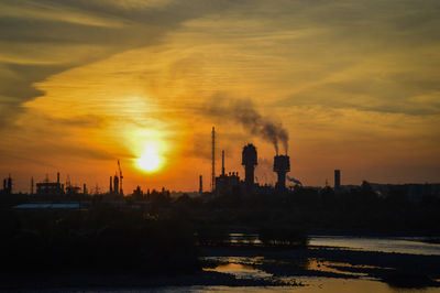 Smoke emitting from factory against sky during sunset