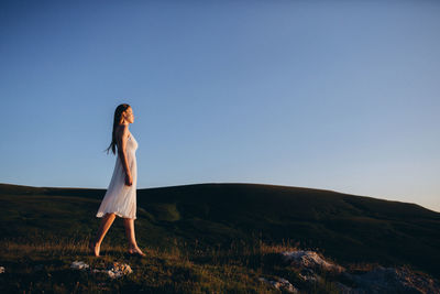 Woman standing on field against clear sky