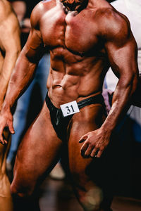 Midsection of shirtless man standing in gym