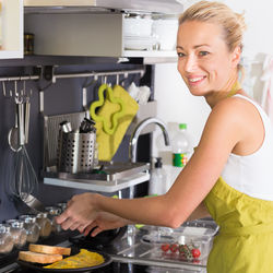 Portrait of mid adult woman preparing food at kitchen