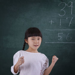 Girl smiling while learning mathematics on blackboard