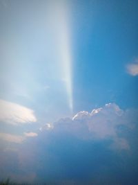 Low angle view of sunlight streaming through clouds