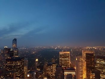 View of illuminated cityscape against blue sky at dusk