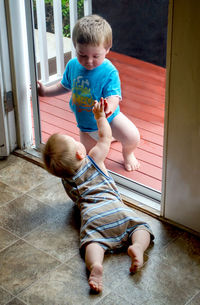 Brothers touch through screen door, one indoors and one outside