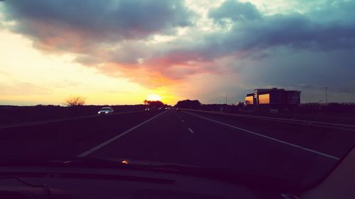 Cars on road against sky during sunset