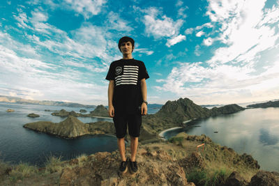 Full length of young man standing on mountain against sky