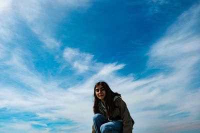 Portrait of smiling young woman against blue sky