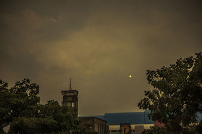 Low angle view of silhouette trees and buildings against sky