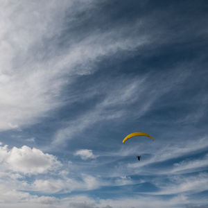 Low angle view of person paragliding against sky