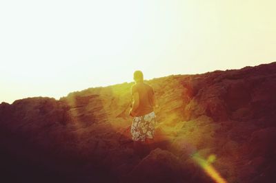 Rear view of man standing on mountain against clear sky