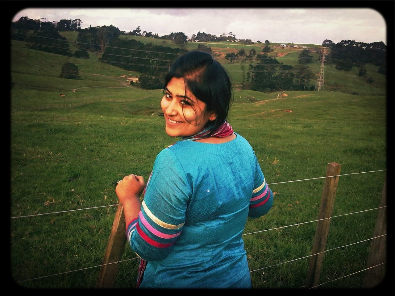 person, grass, transfer print, field, casual clothing, leisure activity, lifestyles, looking at camera, portrait, smiling, grassy, fence, three quarter length, auto post production filter, standing, childhood, landscape, waist up