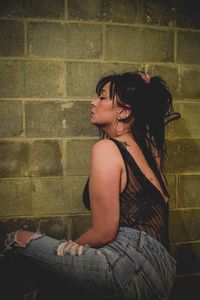 Young woman standing against brick wall