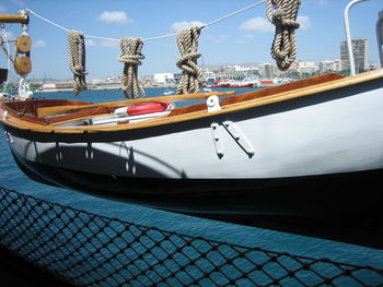 Boats moored at harbor against sky in city