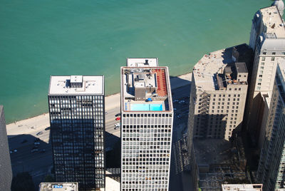 High angle view of buildings by river on sunny day in city