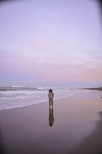 Man standing on beach against sky during sunset