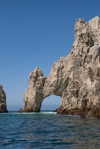 Rock formations in sea against clear blue sky