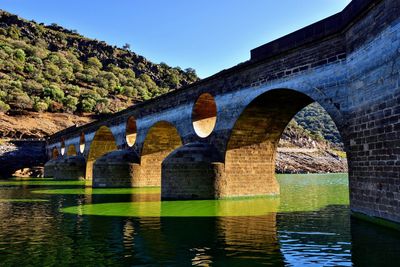 Arch bridge over river against clear sky