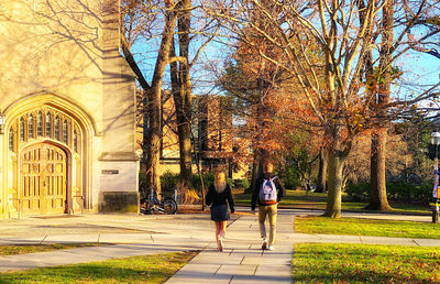 Rear view of people walking on sidewalk during autumn