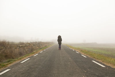 Unrecognisable woman, walking on a cold and foggy mountain road