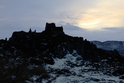 Rock formation on snow against sky during sunset