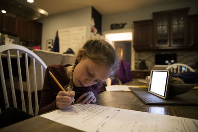 Close-in view of young girl at kitchen table doing school work