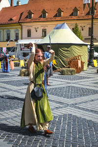 Woman standing on street against buildings in city