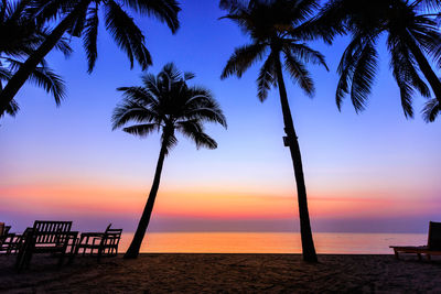 Silhouette palm trees on beach against sky during sunset