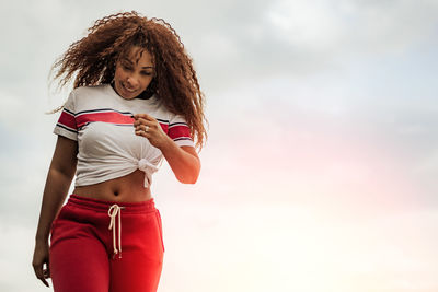 Full length of a beautiful young woman standing against sky