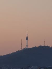 Communications tower in city against sky during sunset