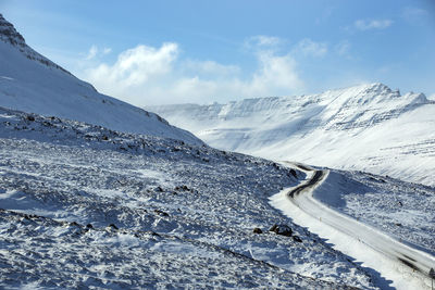 Snowy road with volcanic mountains in wintertime, iceland