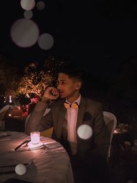 Midsection of woman sitting at restaurant table at night