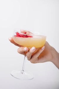 Close-up of hand holding drink against white background