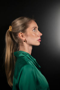 Side view of woman looking away against black background