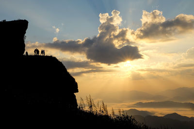 Silhouette people on mountain against sky during sunset