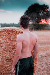 Rear view of shirtless teenage boy standing on land