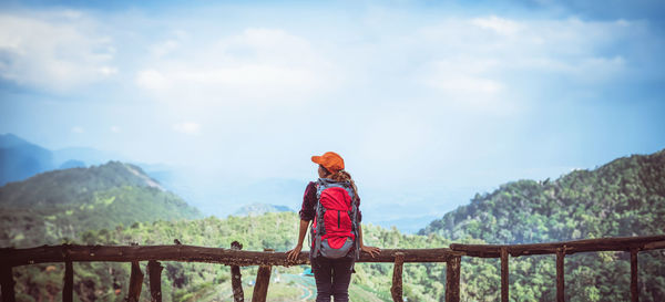 Rear view of woman standing on rock against sky