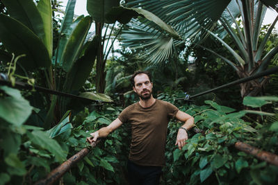 Portrait of smiling young man standing against plants