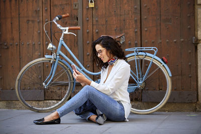 Young woman using her mobile phone with her bike behind on the street. nice afternoon in the city. 