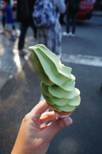 Cropped hand holding ice cream cone on street