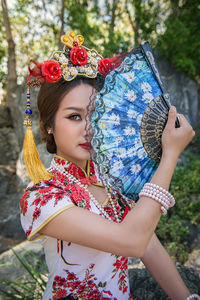 Portrait of young woman wearing qipao holding hand fan