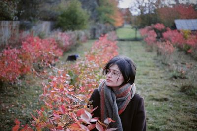 Portrait of young woman standing against plants