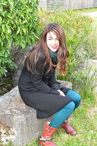 Smiling young woman looking away while sitting on seat at park