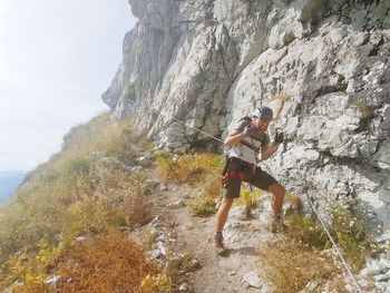 Full length of man climbing rocks in a mountain at heini-holzer-klettersteig